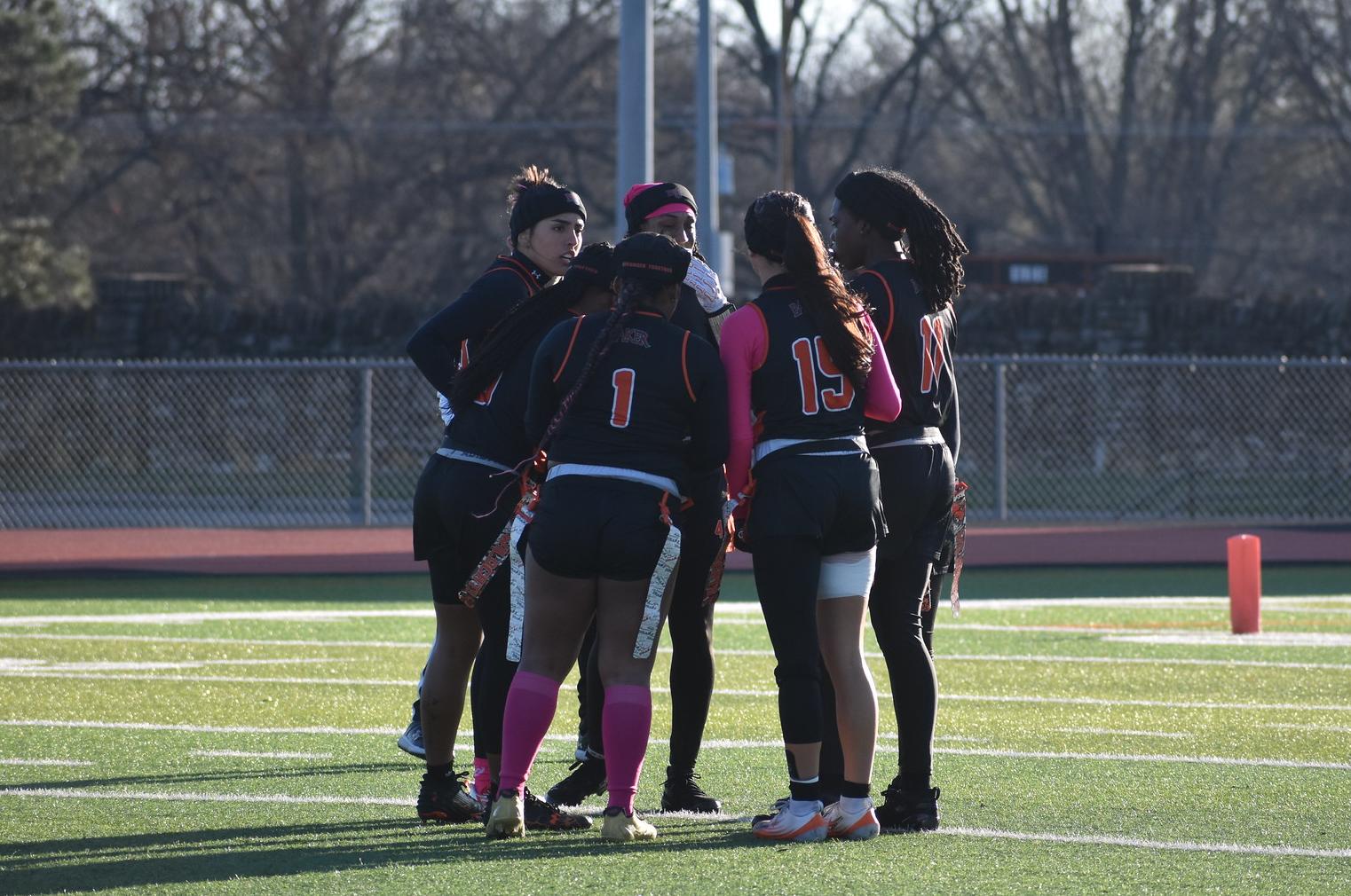Baker women's flag football team huddle at home against Ottawa
